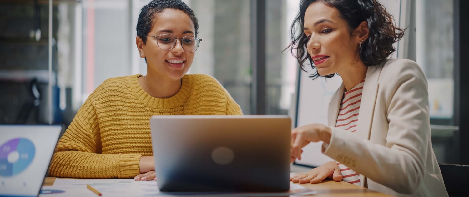 Two people talking while looking at laptop