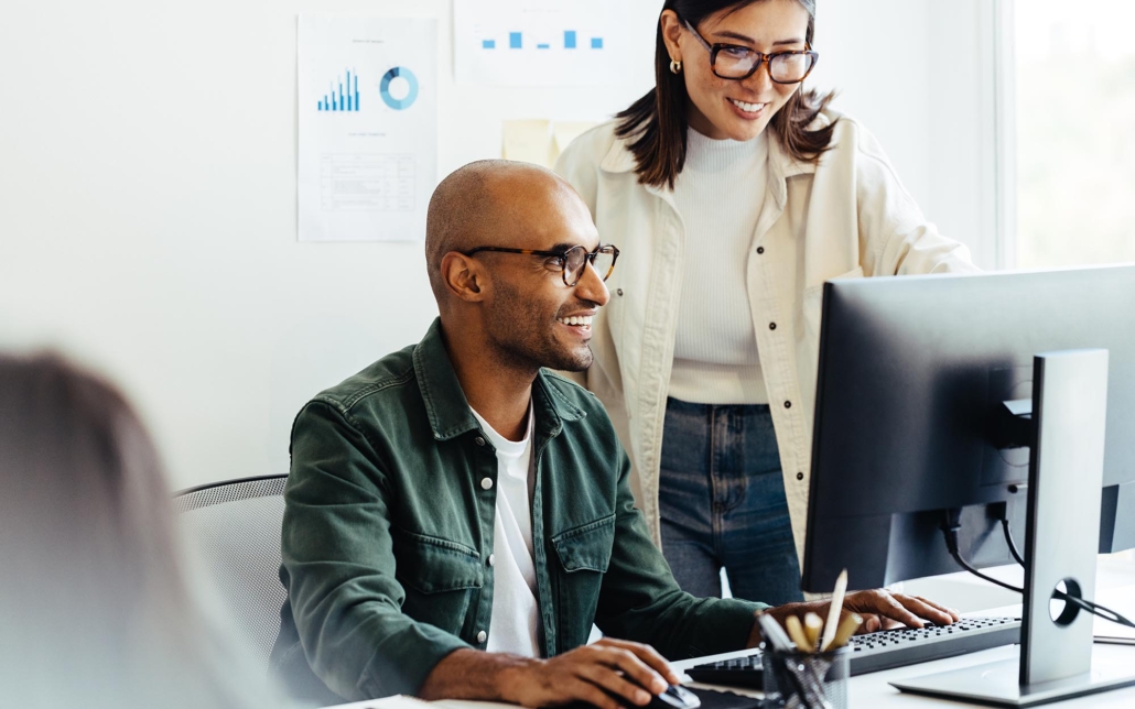 View of two people looking at desktop monitor