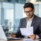 Side view of a man on a laptop looking at documents