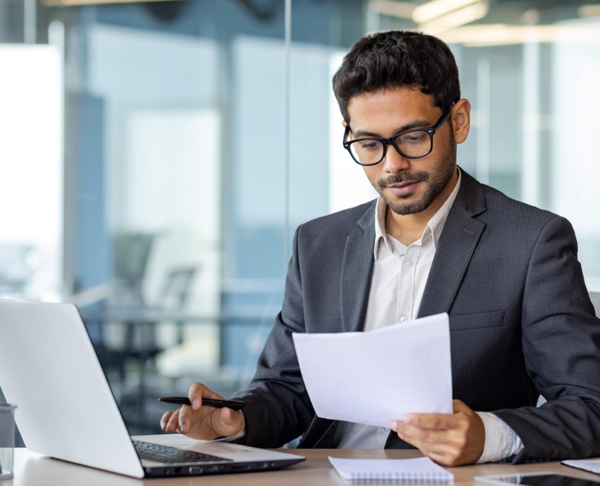 Side view of a man on a laptop looking at documents