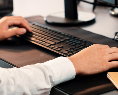 Side view of a man in white dress shirt typing on keyboard